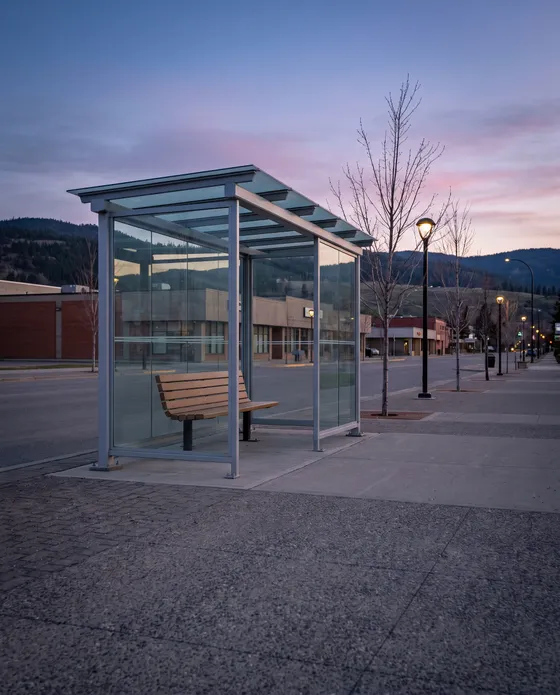 Empty glass bus shelter on a wide street at dusk